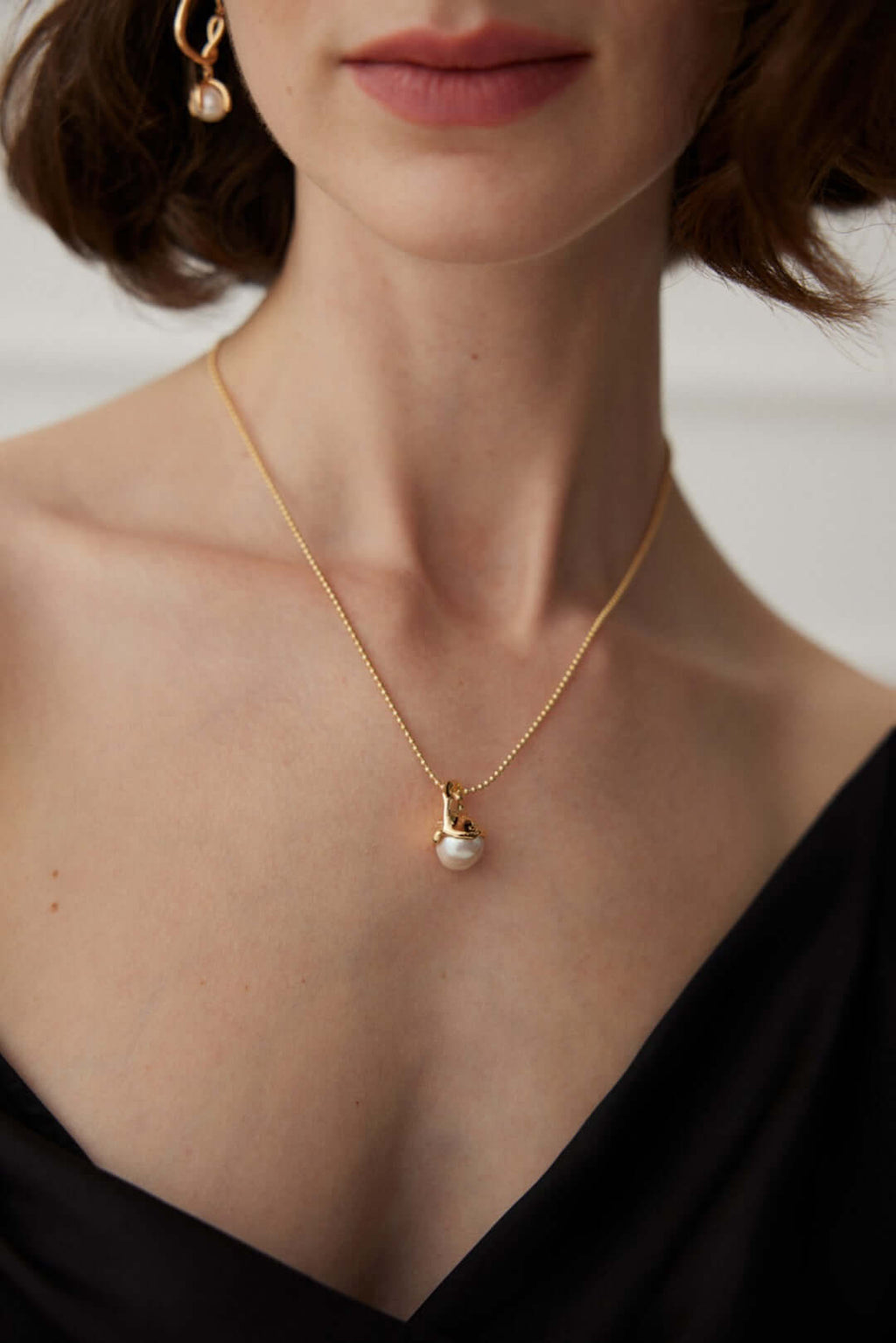 Elegant model wearing the Dawn of the Pearl necklace, showcasing a natural pearl in 14k gold-plated sterling silver.