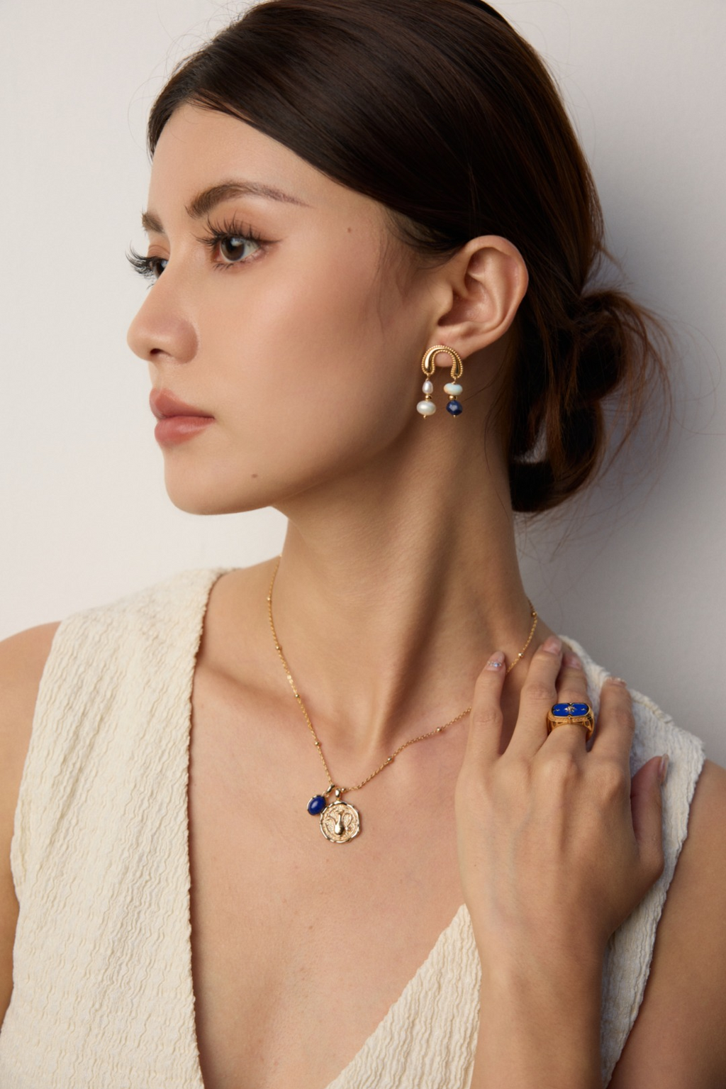 Model wearing gold plated gemstone necklace with blue stone pendant and matching gold earrings and ring