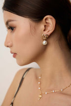 Gold snake knot pearl drop earring on model showcasing unique snake motif jewelry by Mira Aura