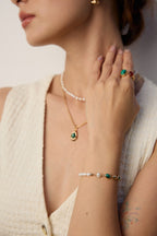 Mira Aura modern gemstone bracelet women with green stones and pearls on a model wrist with rings
