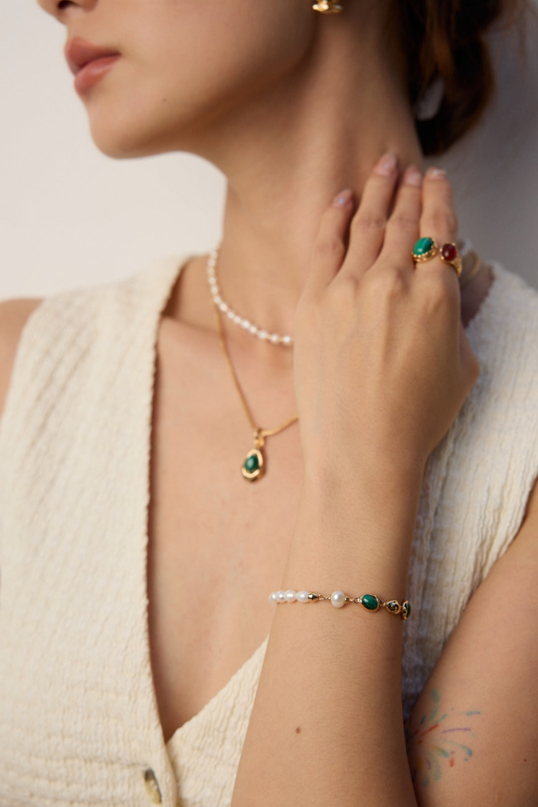 Mira Aura modern gemstone bracelet women with green stones and pearls on a model wrist with rings