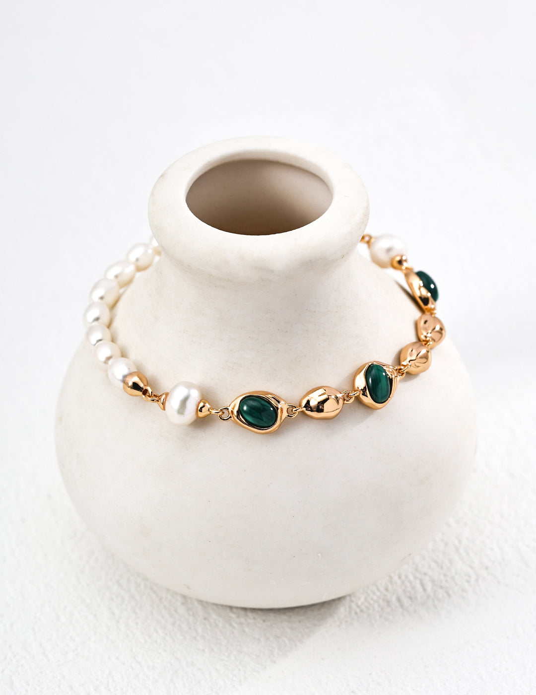 Mira Aura modern gemstone bracelet women with freshwater pearls gold links and green malachite stones on white vase
