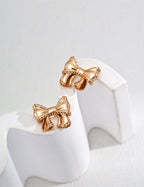 Mira Aura modern gold knot earrings bow shaped polished gold stud earrings on white display stand