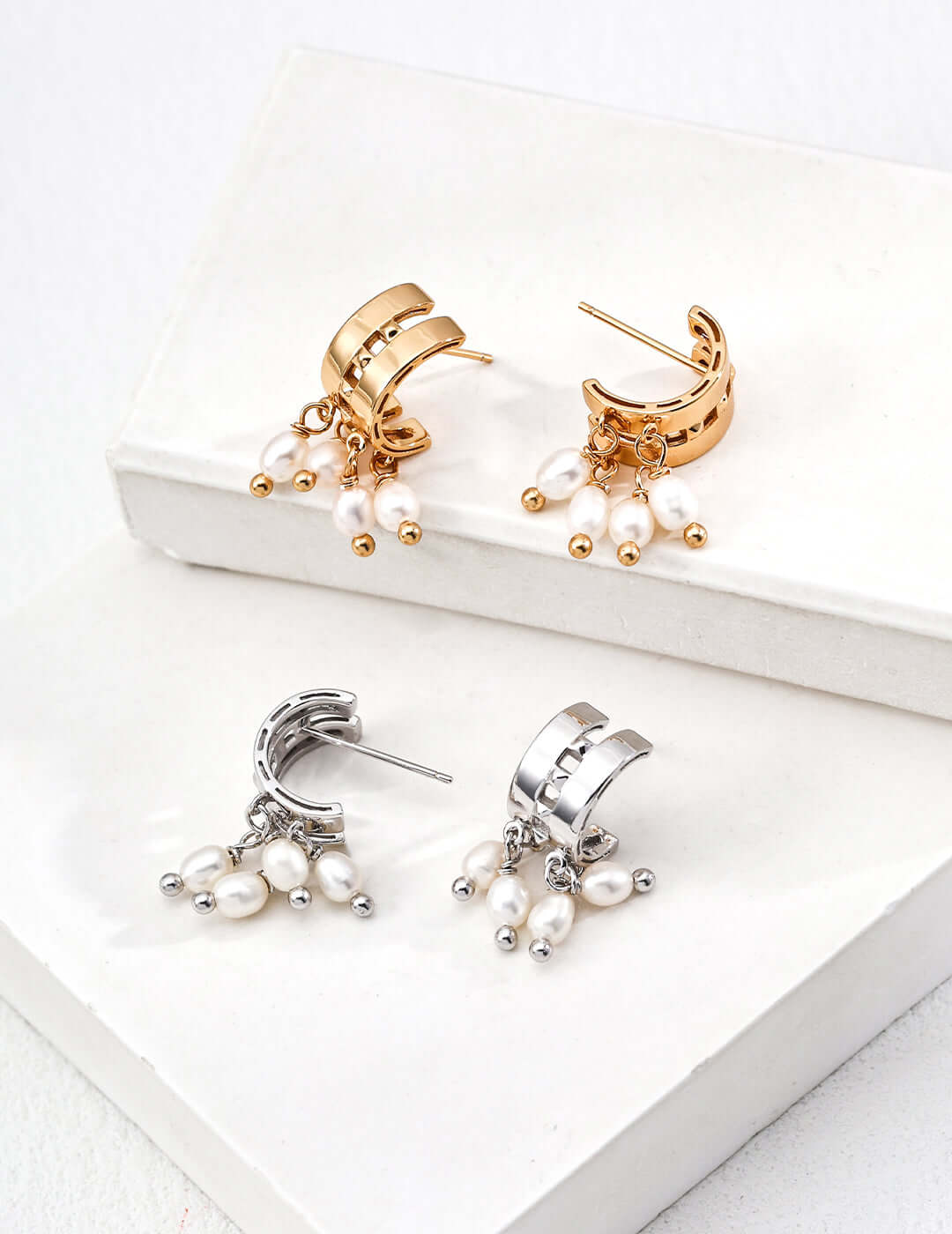 Gold and silver huggie hoop modern pearl earrings for women with dangling freshwater pearls on white display