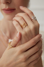 Close up of hands wearing Mira Aura gold and silver name rings with a delicate necklace engraved jewelry gifts for her and him