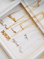 Personalized script nameplate necklaces in gold and silver displayed on white tray engraved jewelry gifts for her and him