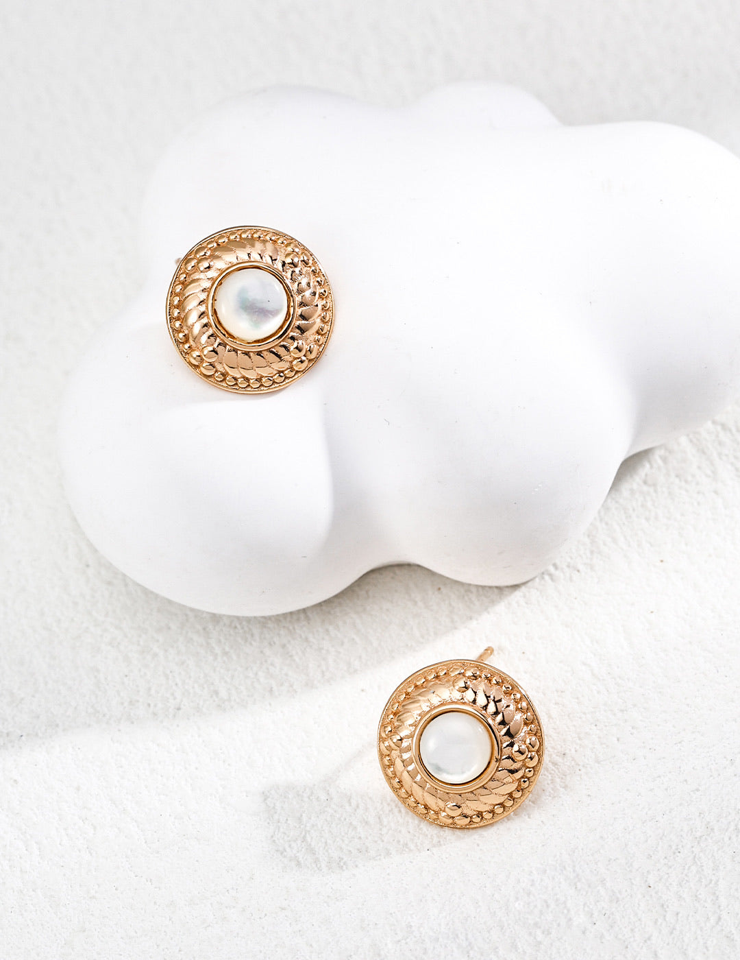 Mira Aura round textured gold earrings with central pearl discs 14k gold plated pearl studs on white sculptural display