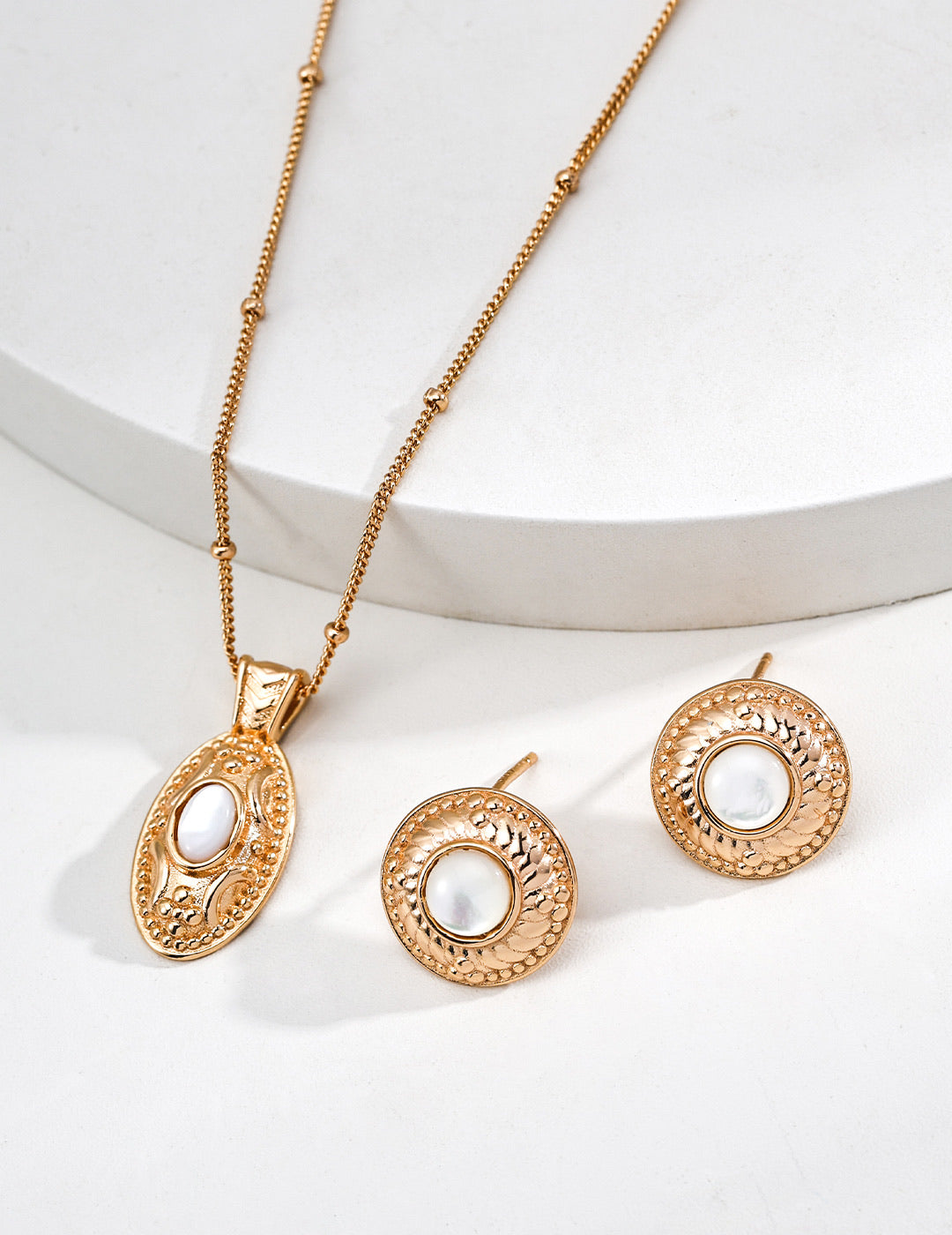 14k gold plated pearl studs paired with matching engraved oval pendant necklace on white background