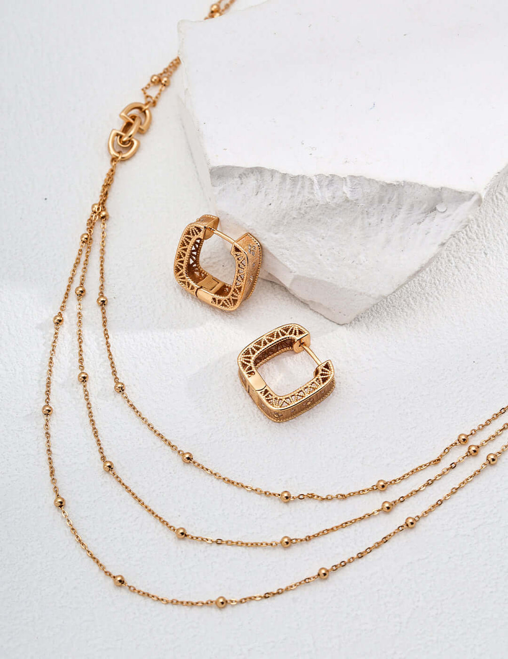 Mira Aura modern gold chain necklace layered three strand beaded chains with carved square hoop gold earrings