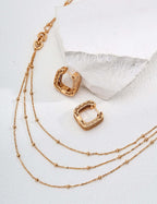 Mira Aura modern gold chain necklace layered three strand beaded chains with carved square hoop gold earrings