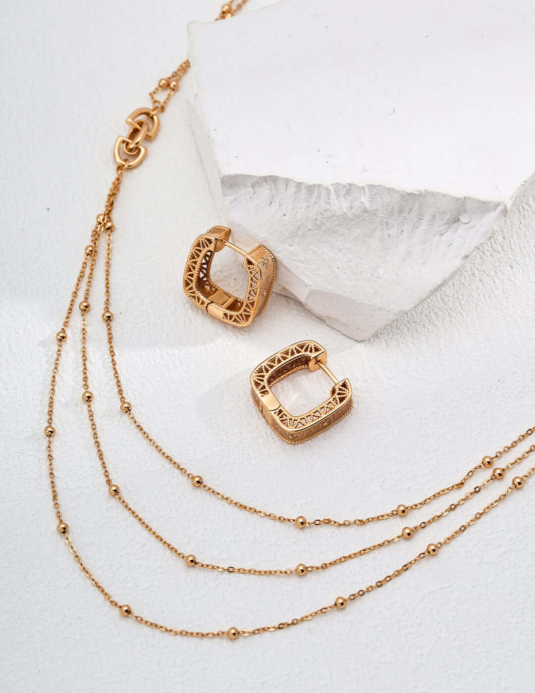 Mira Aura modern gold chain necklace layered three strand beaded chains with carved square hoop gold earrings