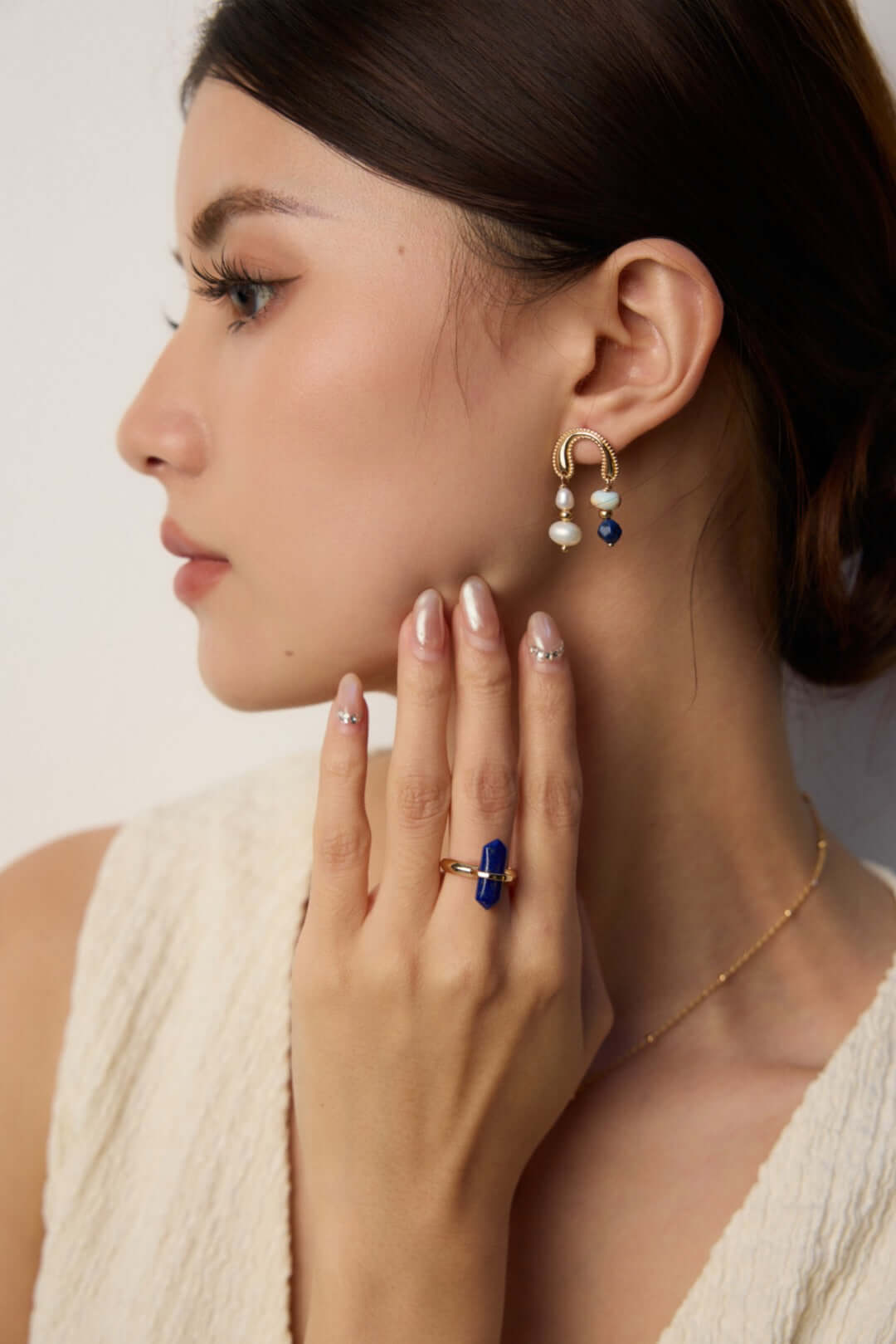 Mira Aura modern pearl gemstone earrings gold drop design with white pearls and deep blue gemstone accents on model