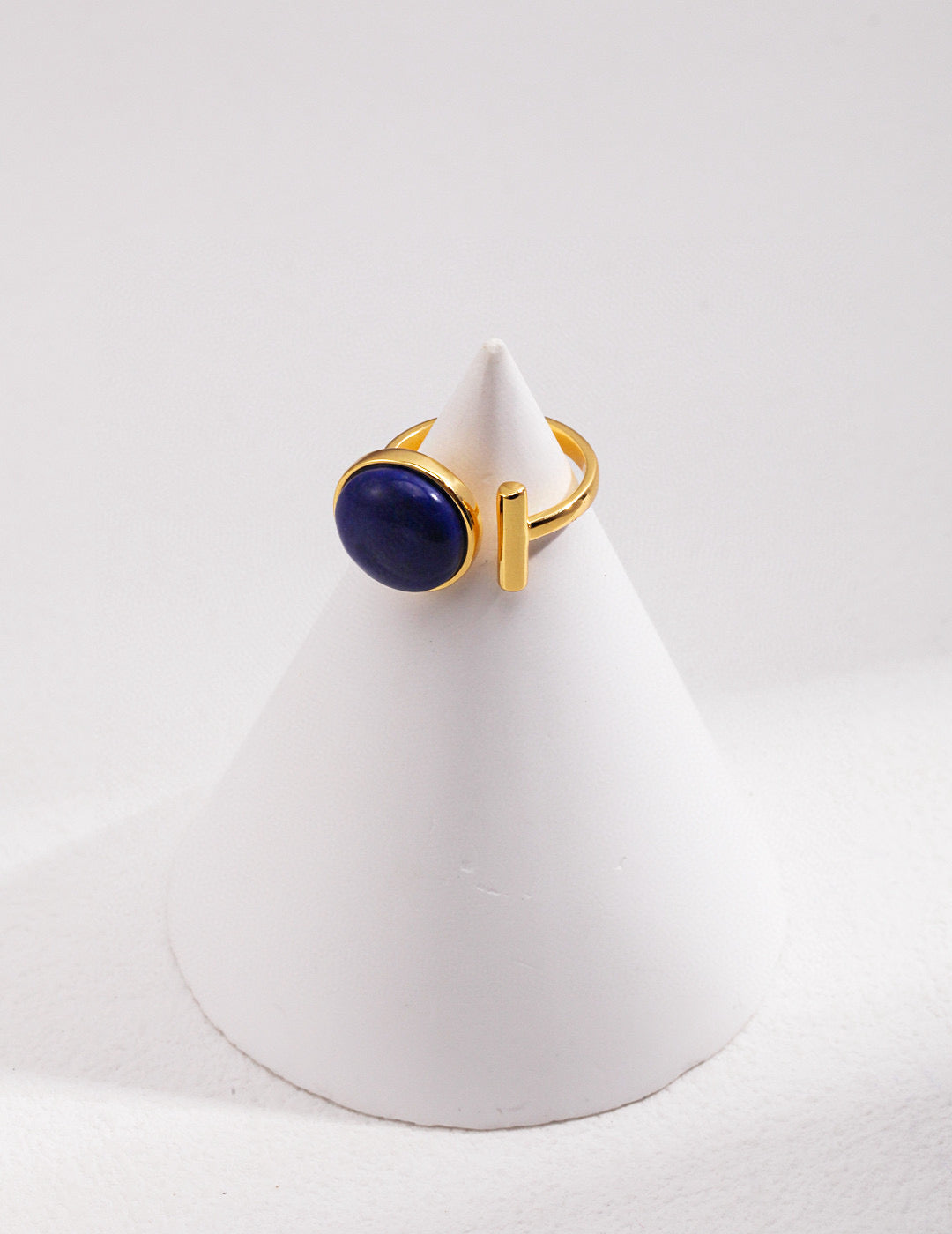 Gold ring with large blue gemstone on white cone display by Mira Aura modern gemstone bracelet women