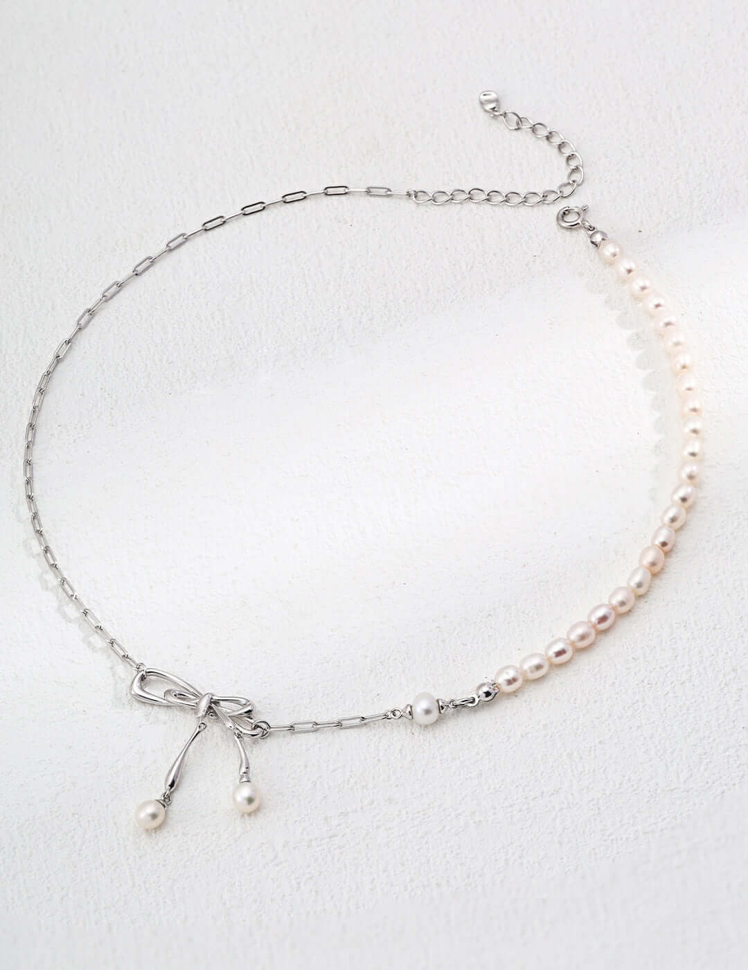 Mira Aura delicate necklace with half pearl strand silver chain and bow with dangling pearls modern pearl jewelry